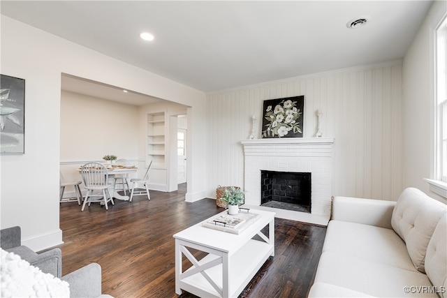 living room with dark hardwood / wood-style floors, a fireplace, and built in shelves