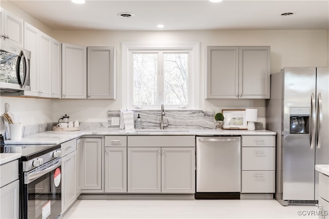 kitchen featuring gray cabinetry, light stone countertops, sink, and appliances with stainless steel finishes