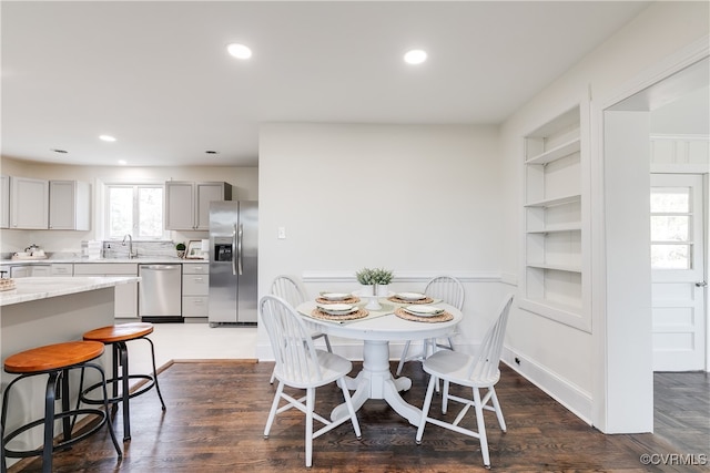 dining room with built in shelves, dark hardwood / wood-style floors, and sink