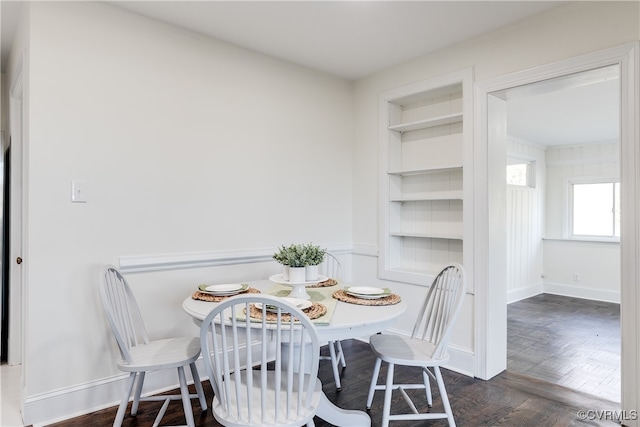 dining space with built in shelves and dark parquet flooring