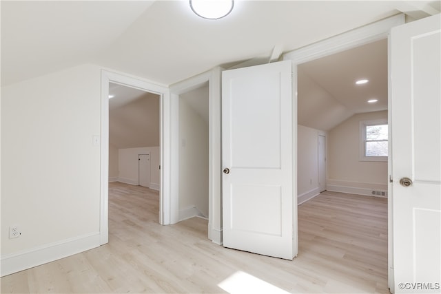 additional living space with light hardwood / wood-style flooring and lofted ceiling