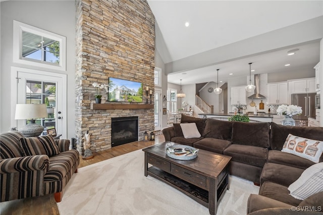 living room featuring a stone fireplace, high vaulted ceiling, and light hardwood / wood-style flooring