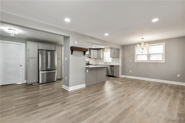 kitchen featuring appliances with stainless steel finishes, gray cabinets, hanging light fixtures, and light hardwood / wood-style floors