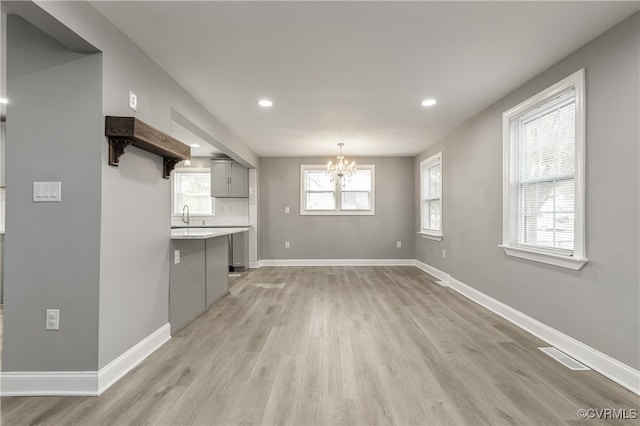 interior space featuring light hardwood / wood-style floors, sink, a wealth of natural light, and an inviting chandelier