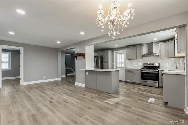 kitchen featuring appliances with stainless steel finishes, gray cabinets, plenty of natural light, and wall chimney range hood