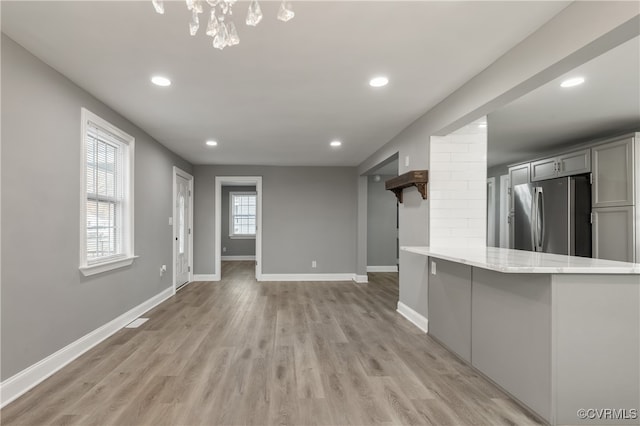 kitchen featuring gray cabinetry, stainless steel fridge, kitchen peninsula, and light hardwood / wood-style floors