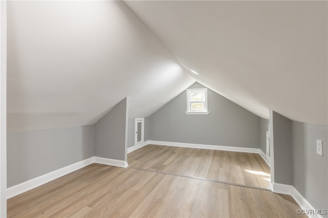 additional living space featuring light wood-type flooring and lofted ceiling