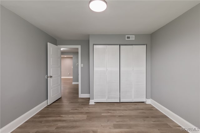 unfurnished bedroom with light wood-type flooring and a closet