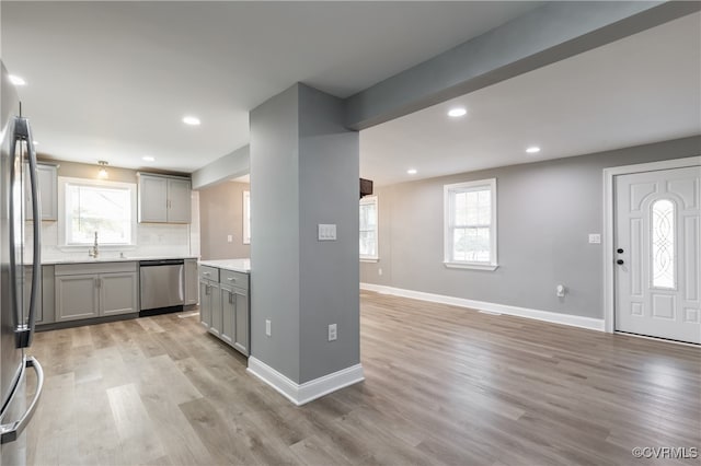 kitchen with stainless steel appliances, gray cabinets, a healthy amount of sunlight, and light hardwood / wood-style floors