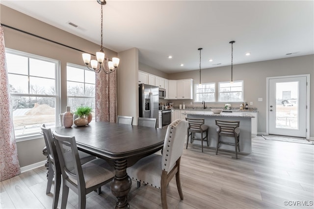 dining area featuring sink, an inviting chandelier, and light hardwood / wood-style floors