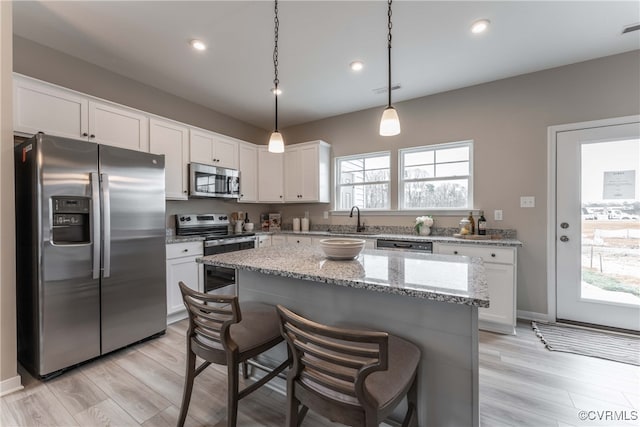 kitchen with a center island, light hardwood / wood-style flooring, white cabinetry, and appliances with stainless steel finishes