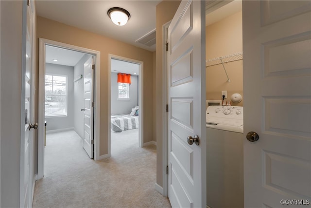 hall with light colored carpet and washer / dryer