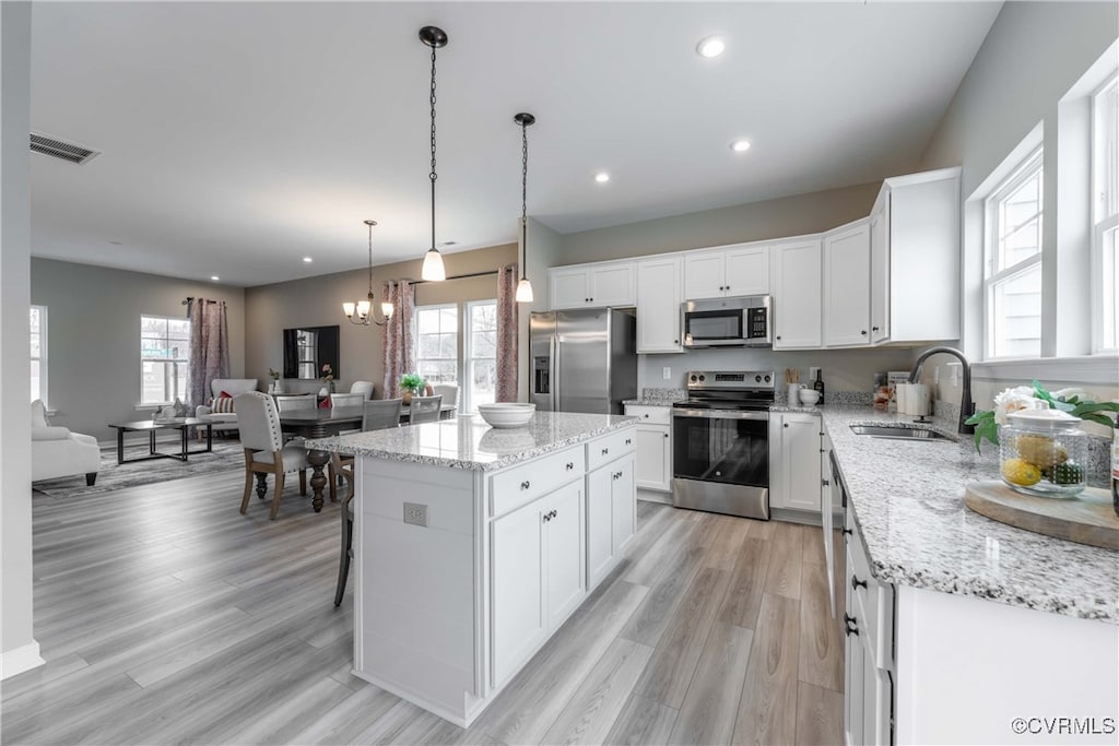 kitchen featuring white cabinetry, sink, a kitchen island, pendant lighting, and stainless steel appliances