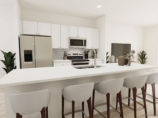 kitchen with white cabinets, sink, an island with sink, light hardwood / wood-style floors, and stainless steel appliances