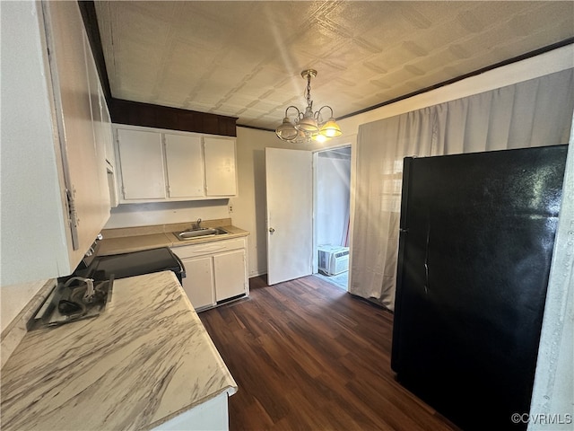 kitchen featuring sink, dark wood-type flooring, hanging light fixtures, black refrigerator, and white cabinets