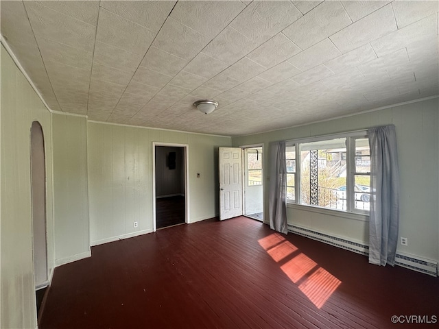 spare room featuring dark wood-type flooring and a baseboard radiator