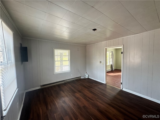 empty room featuring wood walls, dark hardwood / wood-style flooring, and a baseboard heating unit