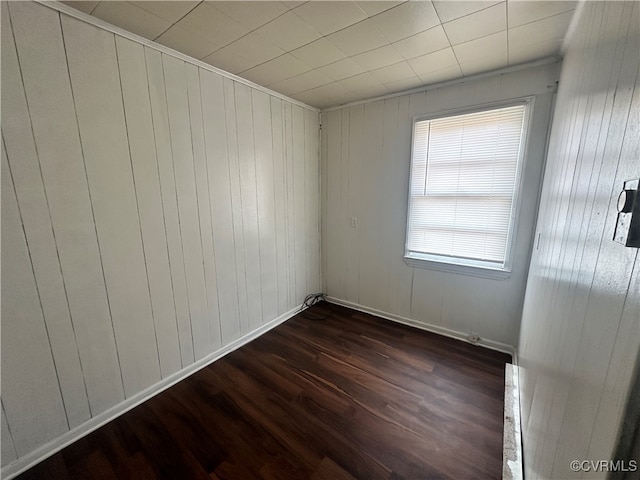 unfurnished room with dark wood-type flooring and wood walls