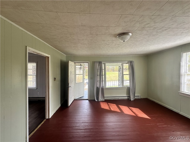 spare room featuring dark hardwood / wood-style floors, baseboard heating, and ornamental molding