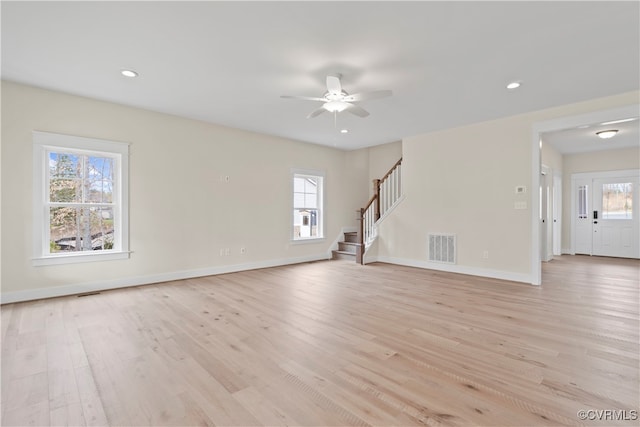 unfurnished living room with light wood-type flooring, a wealth of natural light, and ceiling fan