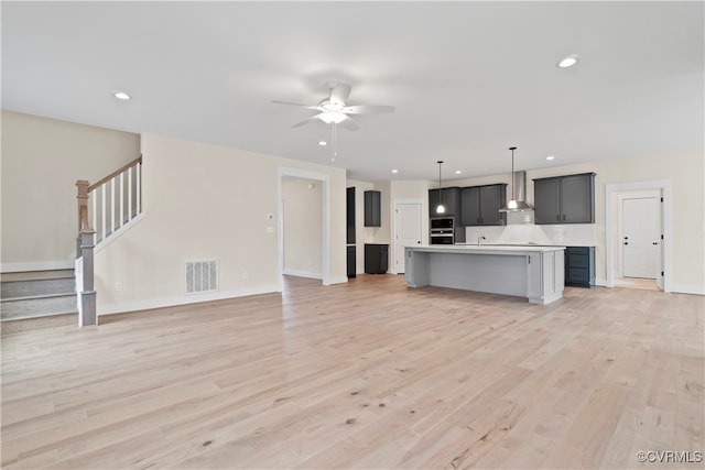 unfurnished living room featuring light hardwood / wood-style floors, ceiling fan, and sink