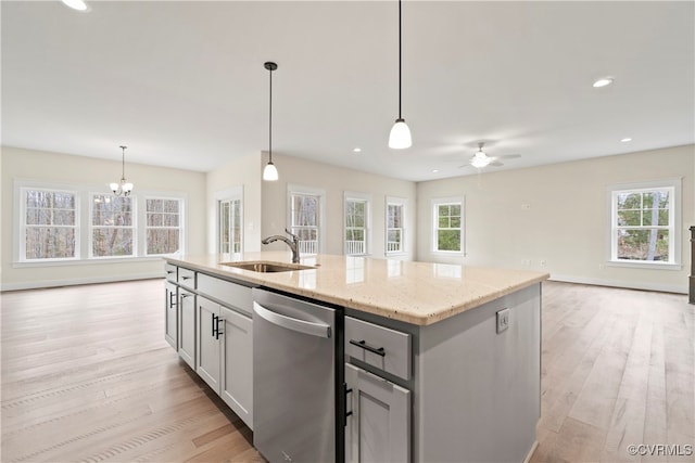 kitchen with plenty of natural light, stainless steel dishwasher, a center island with sink, and sink