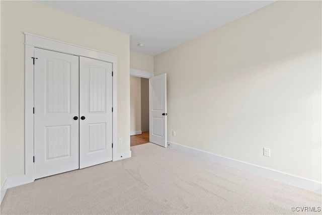 unfurnished bedroom with light carpet and a closet