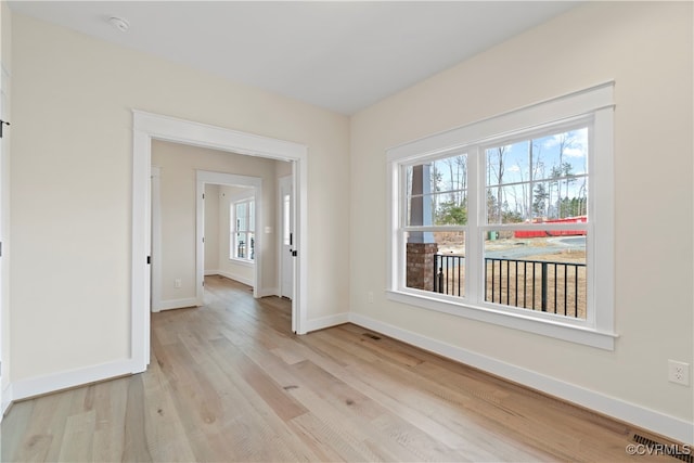 spare room with a wealth of natural light and light hardwood / wood-style flooring