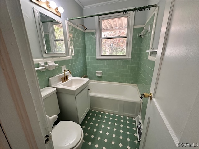 full bathroom with ornamental molding, vanity, tile walls, toilet, and tiled shower / bath