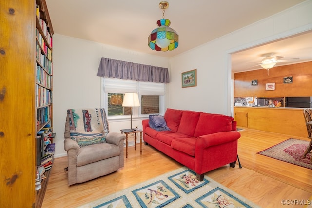 living room with hardwood / wood-style floors, ceiling fan, and ornamental molding