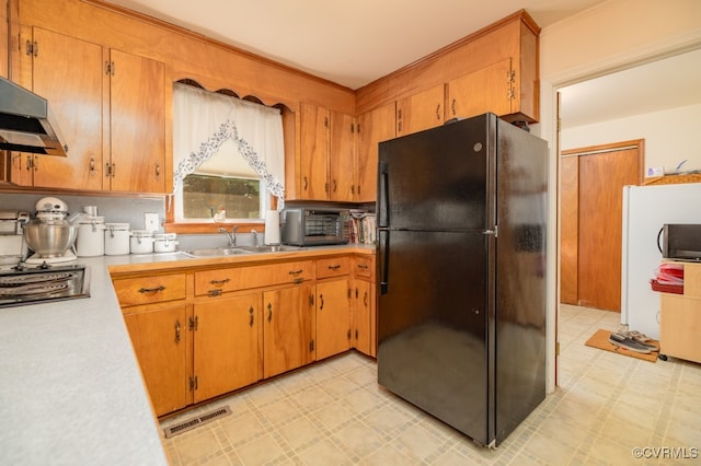 kitchen with backsplash, black fridge, and sink