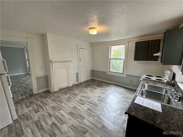 kitchen featuring dark stone counters, a textured ceiling, white range, sink, and hardwood / wood-style floors