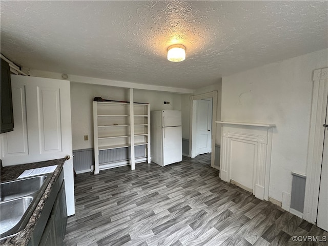 kitchen featuring hardwood / wood-style flooring, white fridge, sink, and a textured ceiling