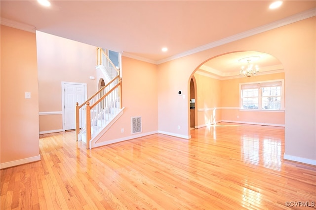 empty room featuring light wood-type flooring, ornamental molding, and a chandelier