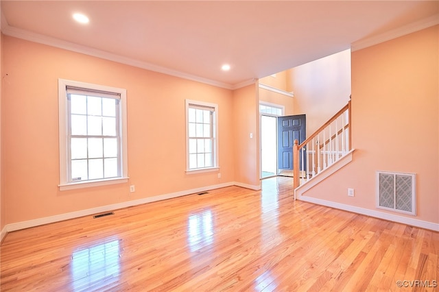 unfurnished living room featuring light hardwood / wood-style floors, a wealth of natural light, and crown molding