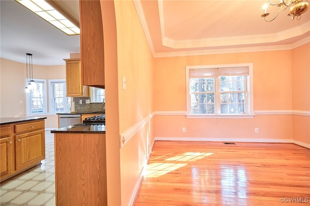 kitchen with backsplash, stainless steel dishwasher, crown molding, light hardwood / wood-style floors, and hanging light fixtures