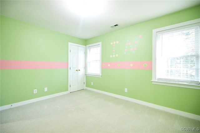 unfurnished room featuring plenty of natural light and light carpet