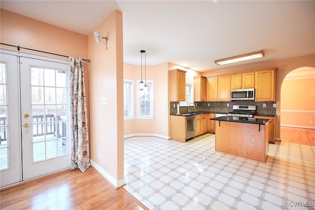 kitchen featuring pendant lighting, a center island, stainless steel appliances, and a wealth of natural light