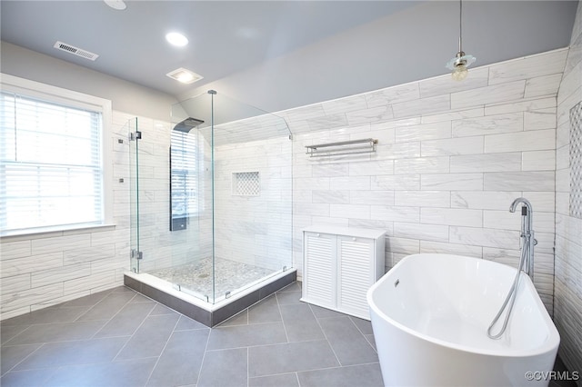 bathroom with tile patterned flooring, tile walls, and shower with separate bathtub