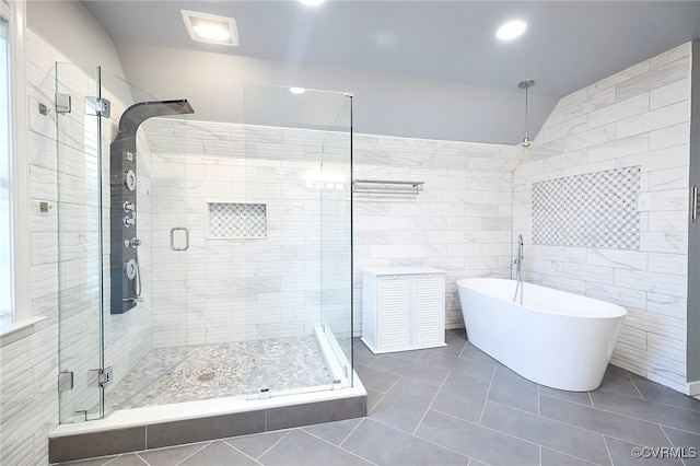 bathroom with tile patterned flooring, shower with separate bathtub, and tile walls