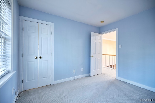 unfurnished bedroom with light colored carpet and a closet