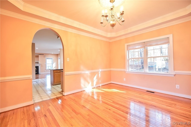 unfurnished room featuring a notable chandelier, ornamental molding, and light hardwood / wood-style flooring