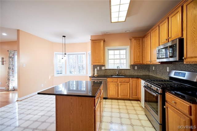 kitchen with sink, hanging light fixtures, decorative backsplash, a kitchen island, and appliances with stainless steel finishes