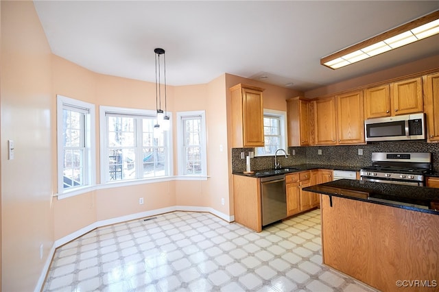 kitchen with a wealth of natural light, sink, hanging light fixtures, and appliances with stainless steel finishes