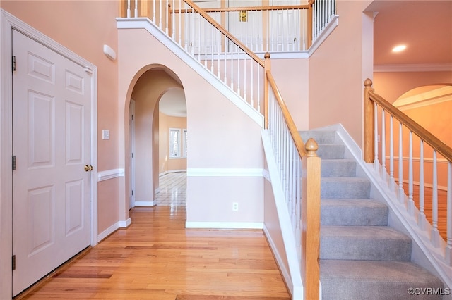 stairs with hardwood / wood-style floors, a high ceiling, and ornamental molding