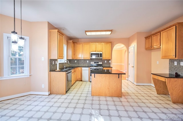 kitchen featuring sink, decorative light fixtures, decorative backsplash, a kitchen island, and appliances with stainless steel finishes