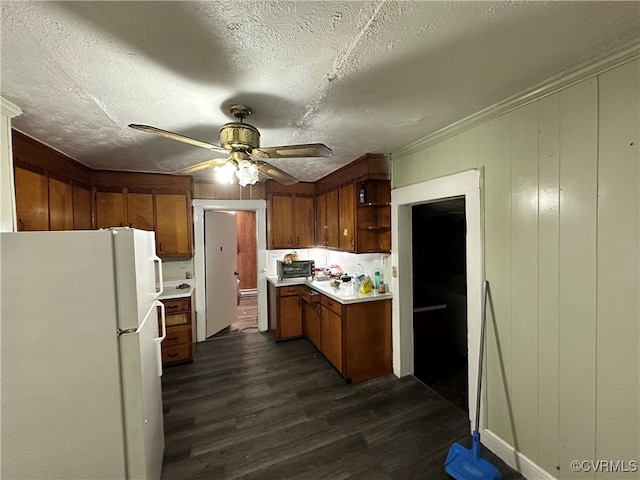 kitchen with dark hardwood / wood-style flooring, ornamental molding, a textured ceiling, ceiling fan, and white fridge