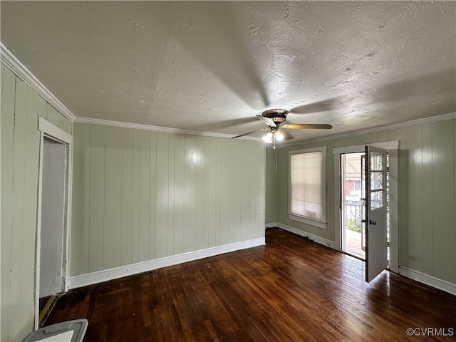 empty room featuring crown molding, ceiling fan, dark wood-type flooring, and wood walls