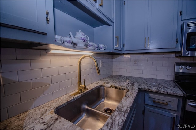 kitchen with decorative backsplash, black range with electric cooktop, light stone countertops, and sink