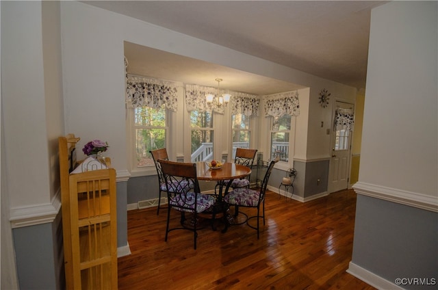 dining space with dark hardwood / wood-style flooring and a chandelier